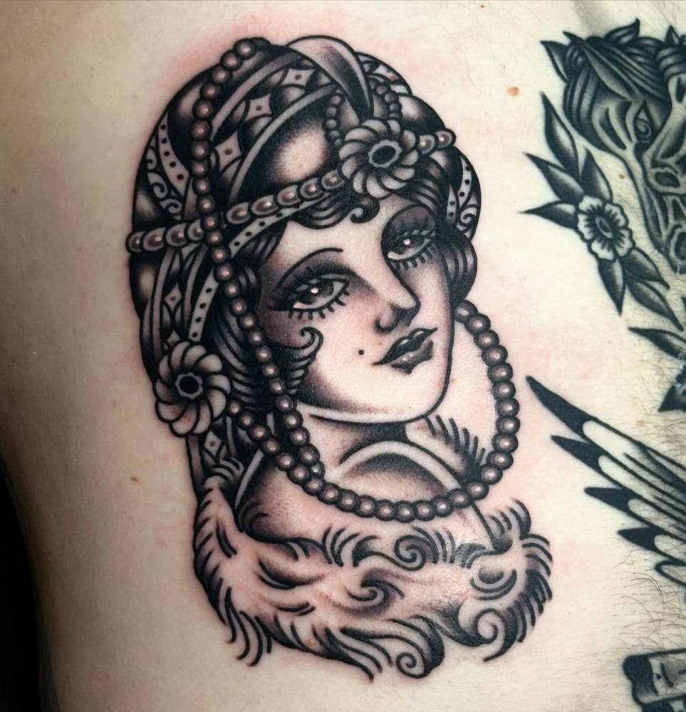 Women portrait tattoo in traditional style located on the rib.