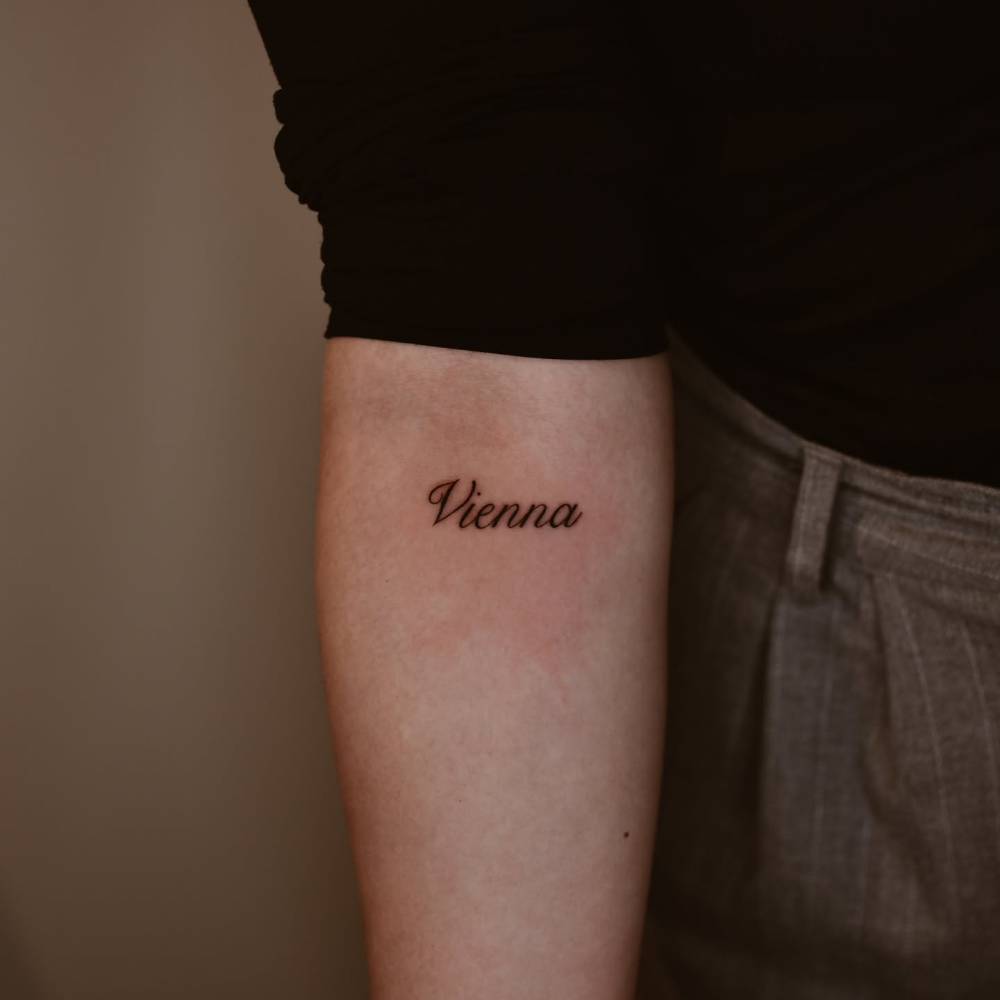 "Vienna" lettering tattoo located on the inner forearm.