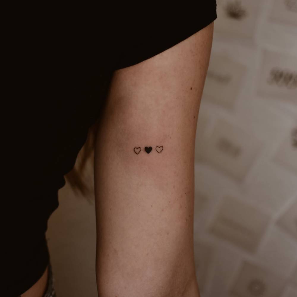 Minimalistic little hearts tattooed on the inner arm.