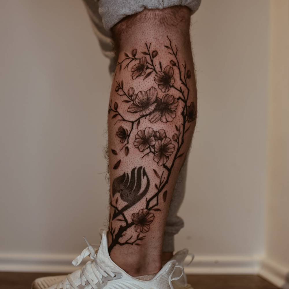 Illustrative style cherry blossom tattoo located on the shin.