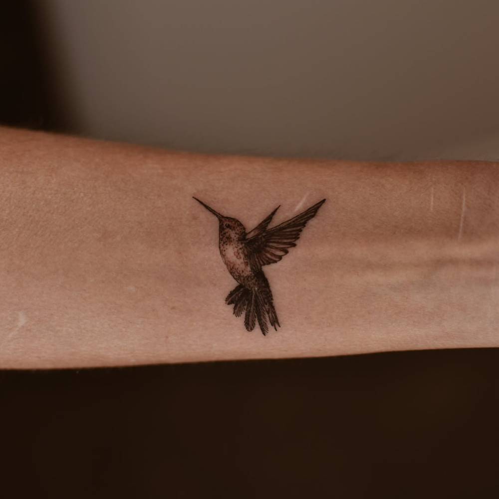 Hummingbird tattoo in blackwork style located on the inner forearm.