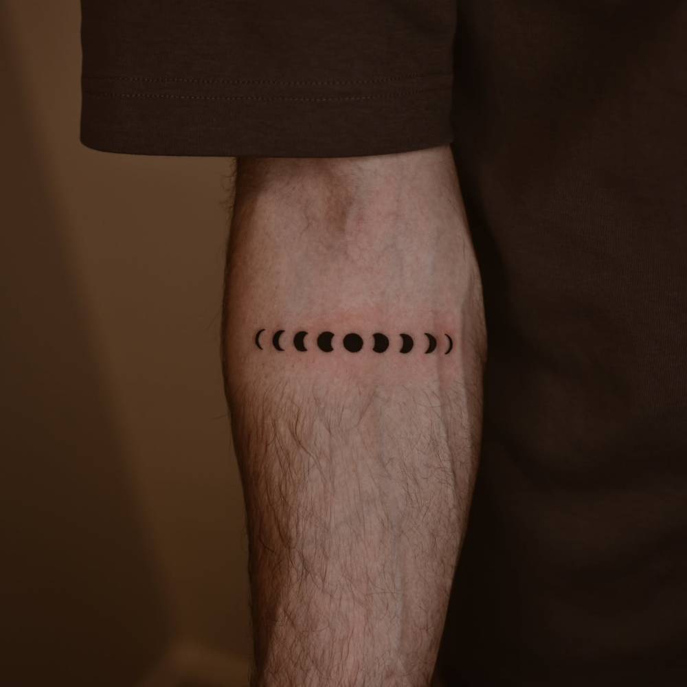 Moon phases tattoo in minimalistic style done on the inner forearm.