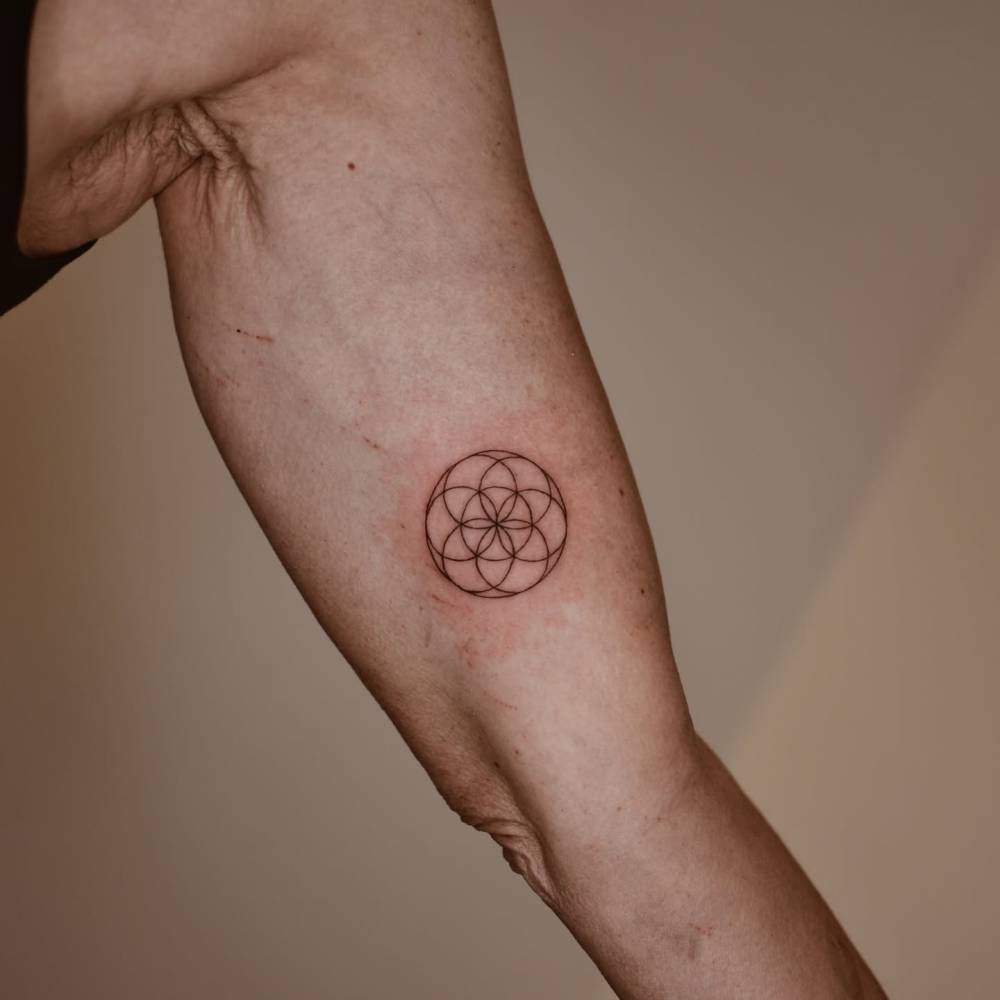 Flower of life tattoo in fine line style located on the inner arm.