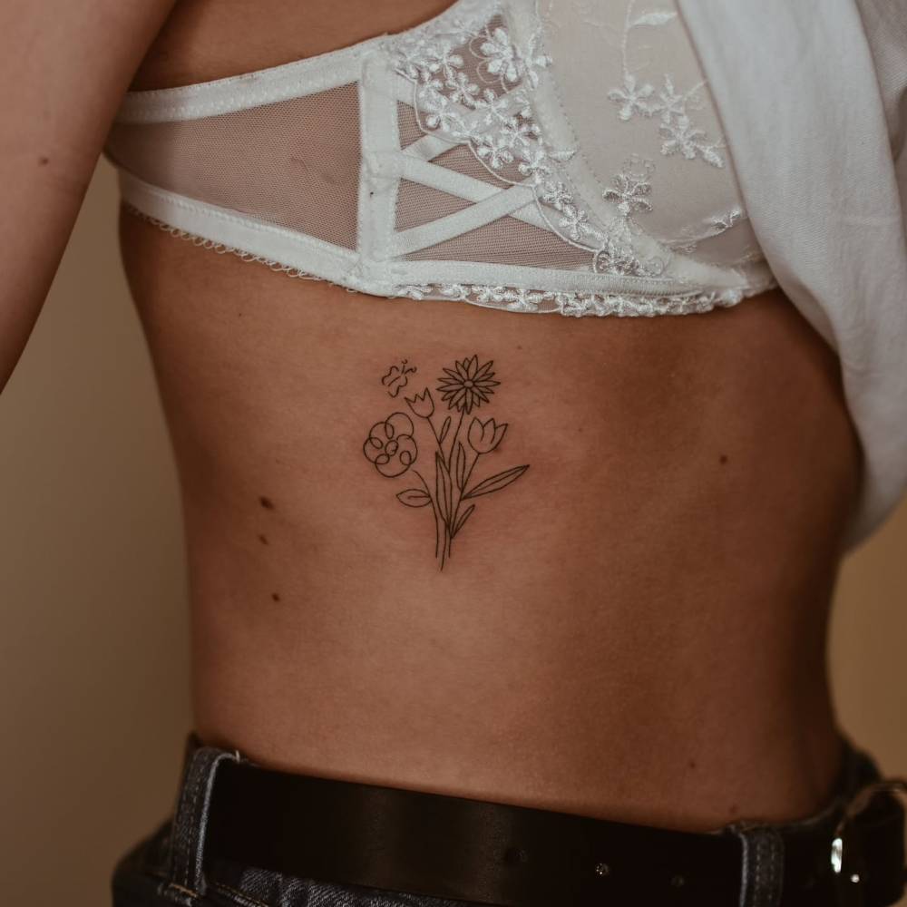 Little flower bouquet tattoo in fine line style placed on the rib.