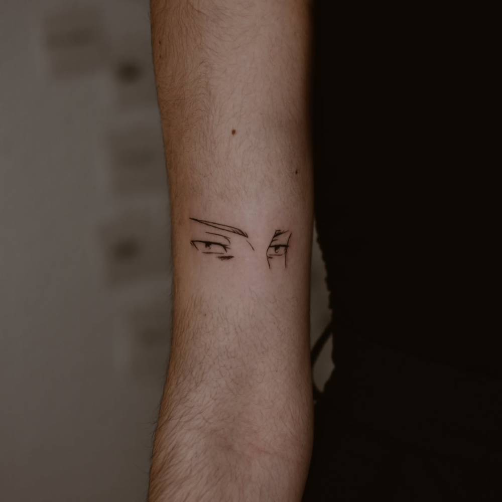 Cartoon style eyes tattoo located on the bicep.