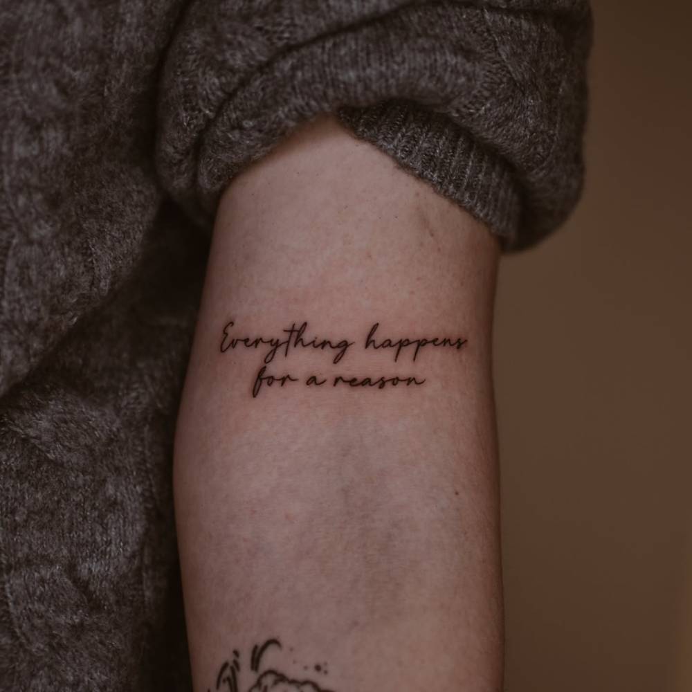 "Everything happens for a reason" in handwritten font tattooed on the bicep.