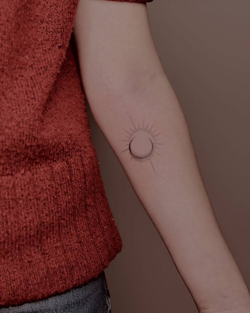 Sun and moon tattoo in fine line style placed on the inner forearm.