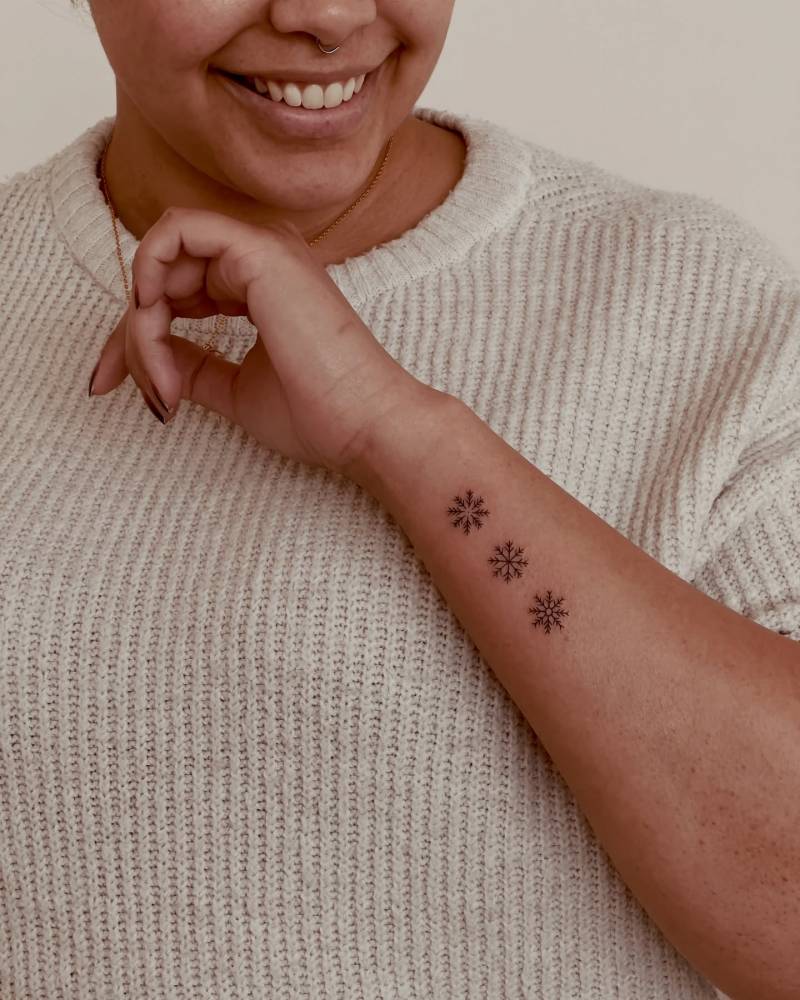Little snowflakes tattoo in fine line style done on the wrist.