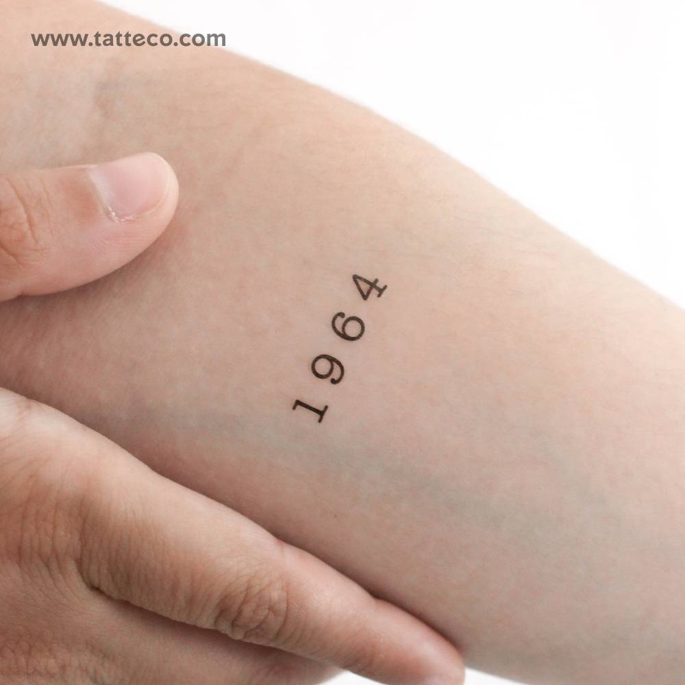 Typewriter font "1964" temporary tattoo located on the inner forearm.