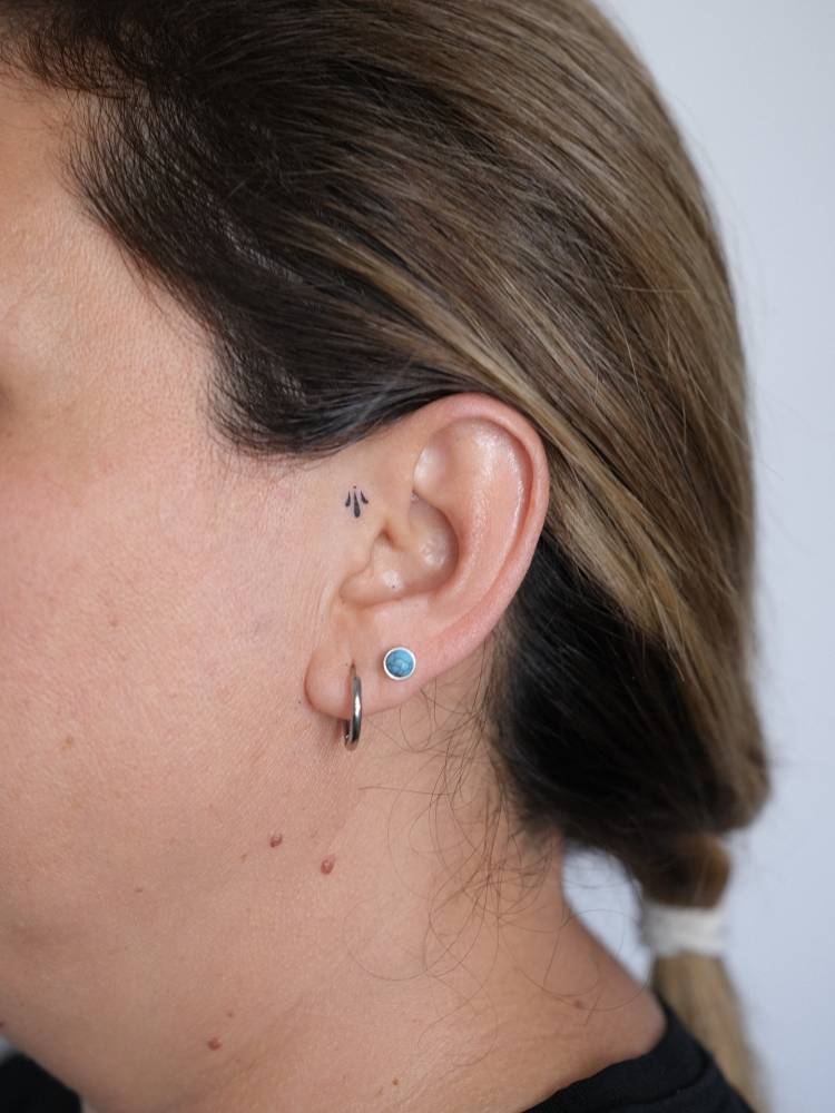 Tiny minimalistic ornamental tattoo located on the ear.