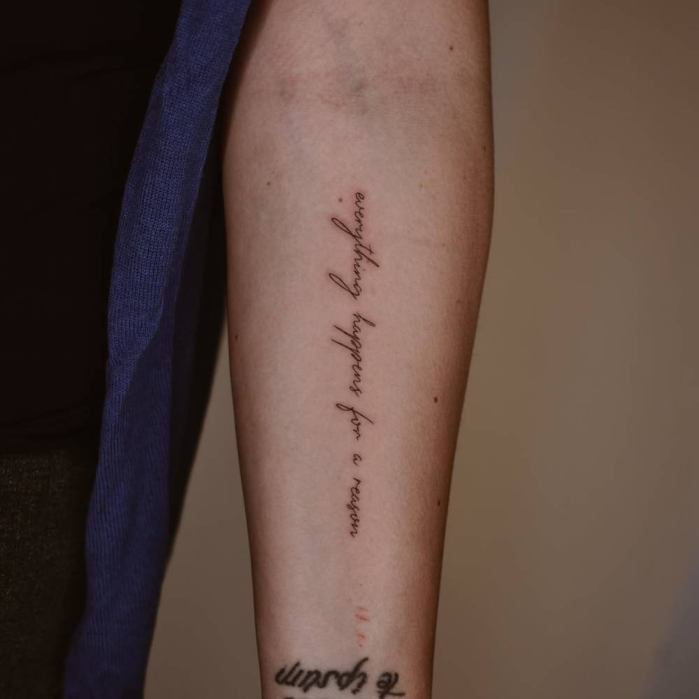 Handwritten font "everything happens for a reason" tattoo placed on the inner forearm.