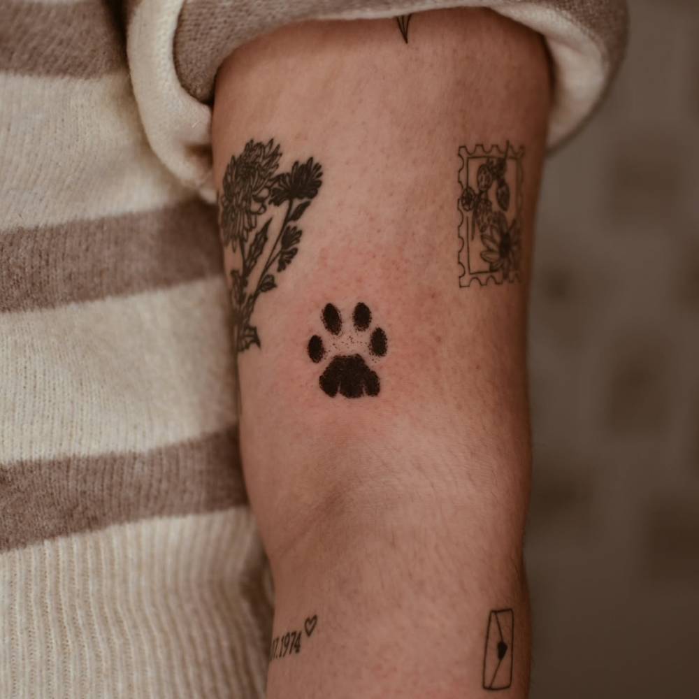 Watercolor style Dog paw print tattoo placed on the upper arm.