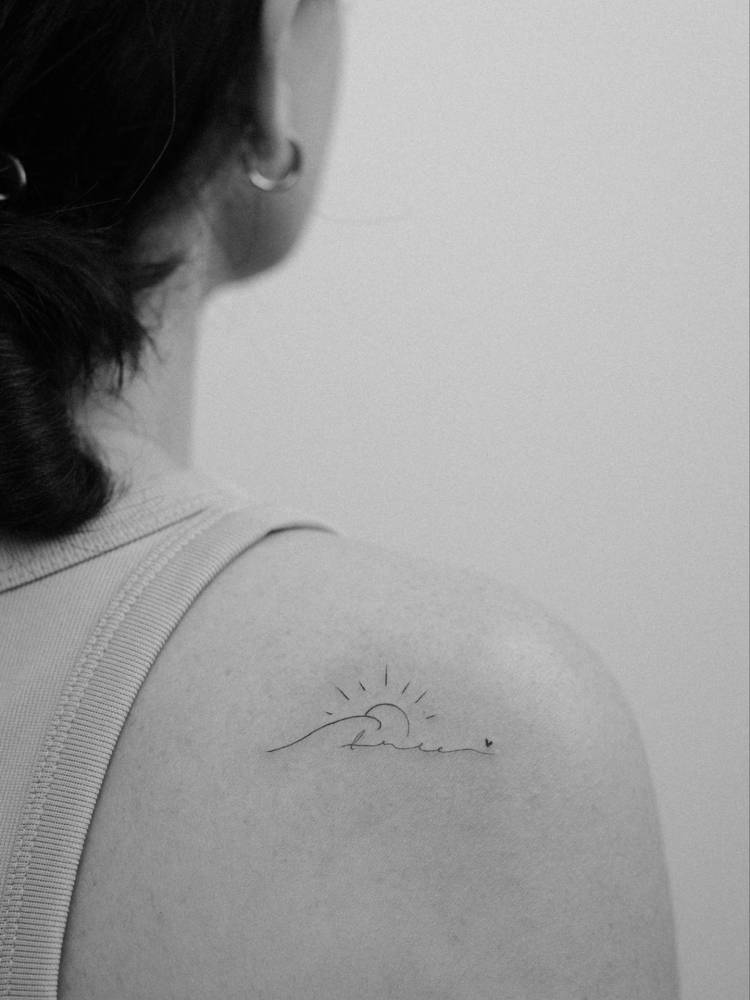 Mountain sunset and handwritten lettering tattoo located on the shoulder blade.