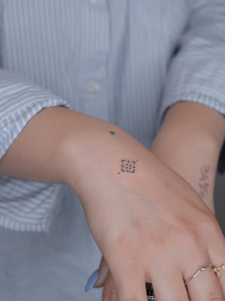 Tiny ornamental tattoo located on the wrist.