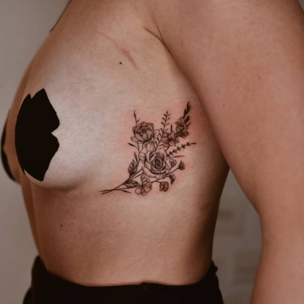 Illustrative style flower bouquet tattoo placed on the side boob.