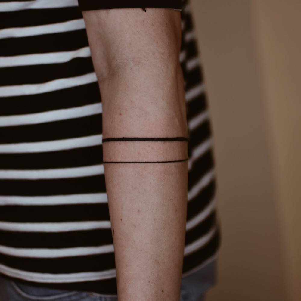 Line bracelets tattoo located on the forearm.