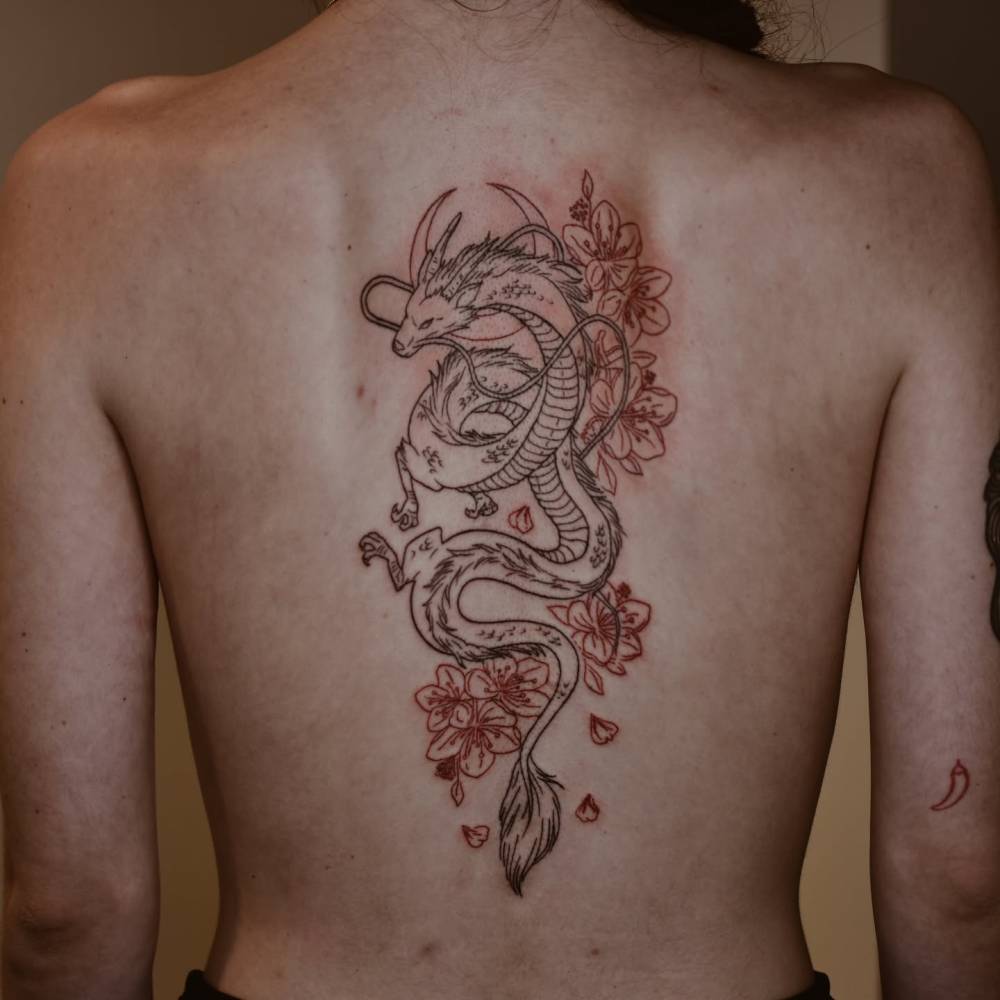 Haku and cherry blossom tattoo located on the back, done in fine line style.
