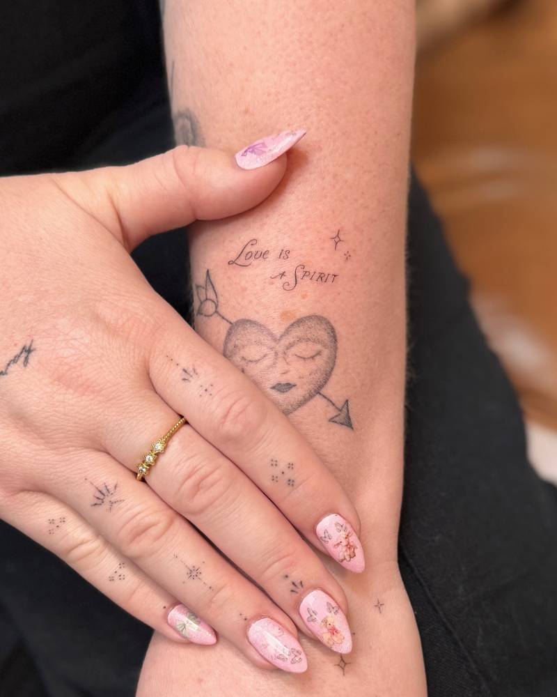 Lettering tattoo that says "love is spirit" located on the forearm.