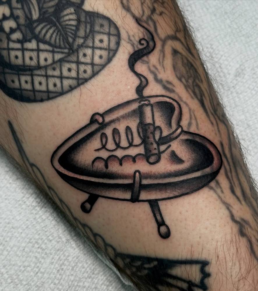 Traditional style ashtray tattoo located on the shin.