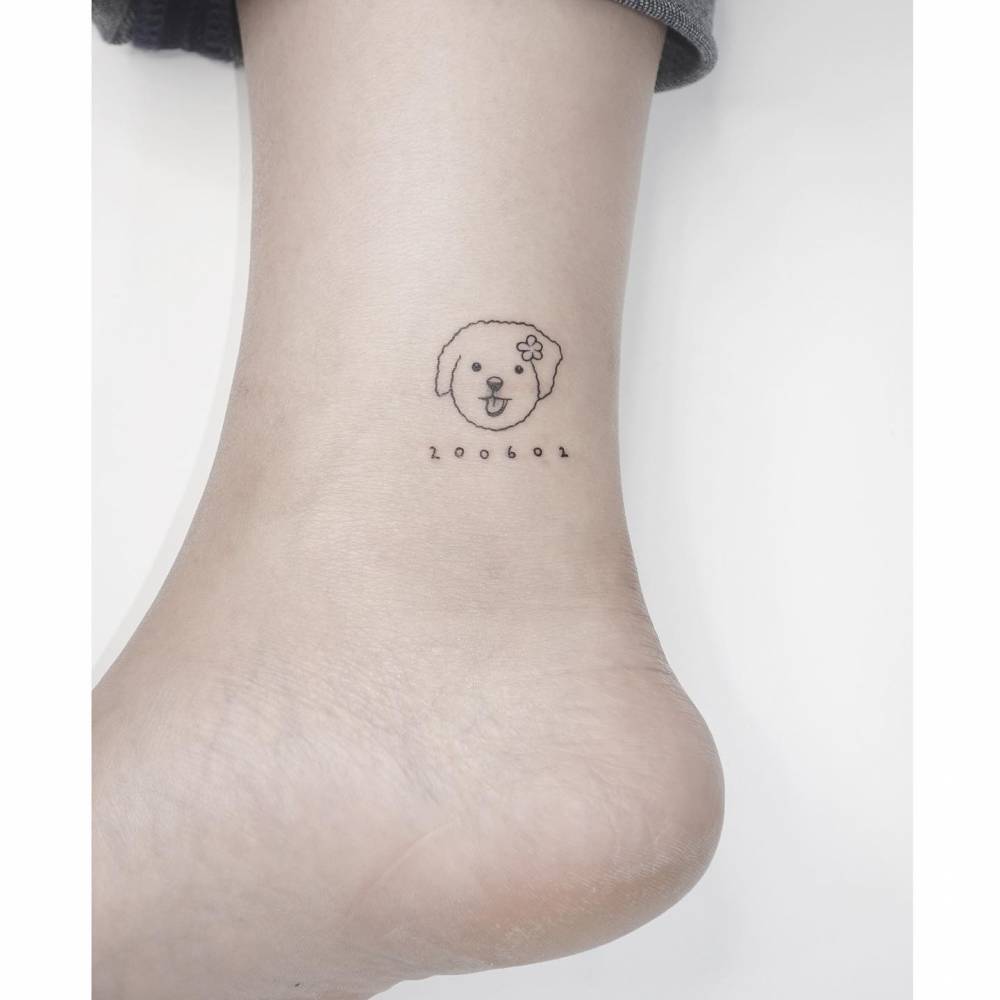 Minimalistic style dog portrait and date tattoo located on the ankle.
