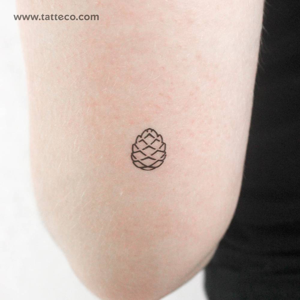 Tiny minimalistic pine cone temporary tattoo located on the inner forearm.