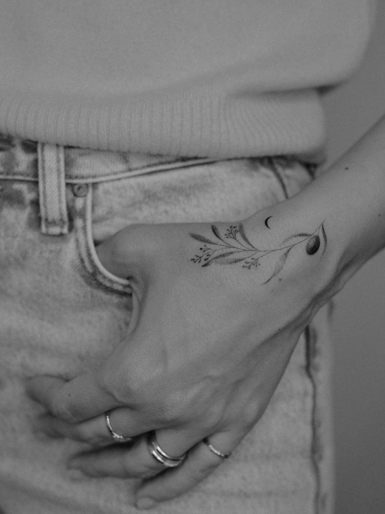 Illustrative style olive branch tattoo located on the wrist.
