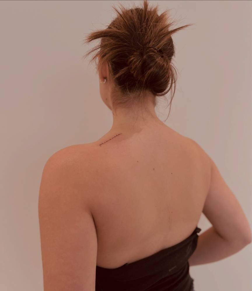 Handwritten font word "primavera" tattooed on the top of shoulder.