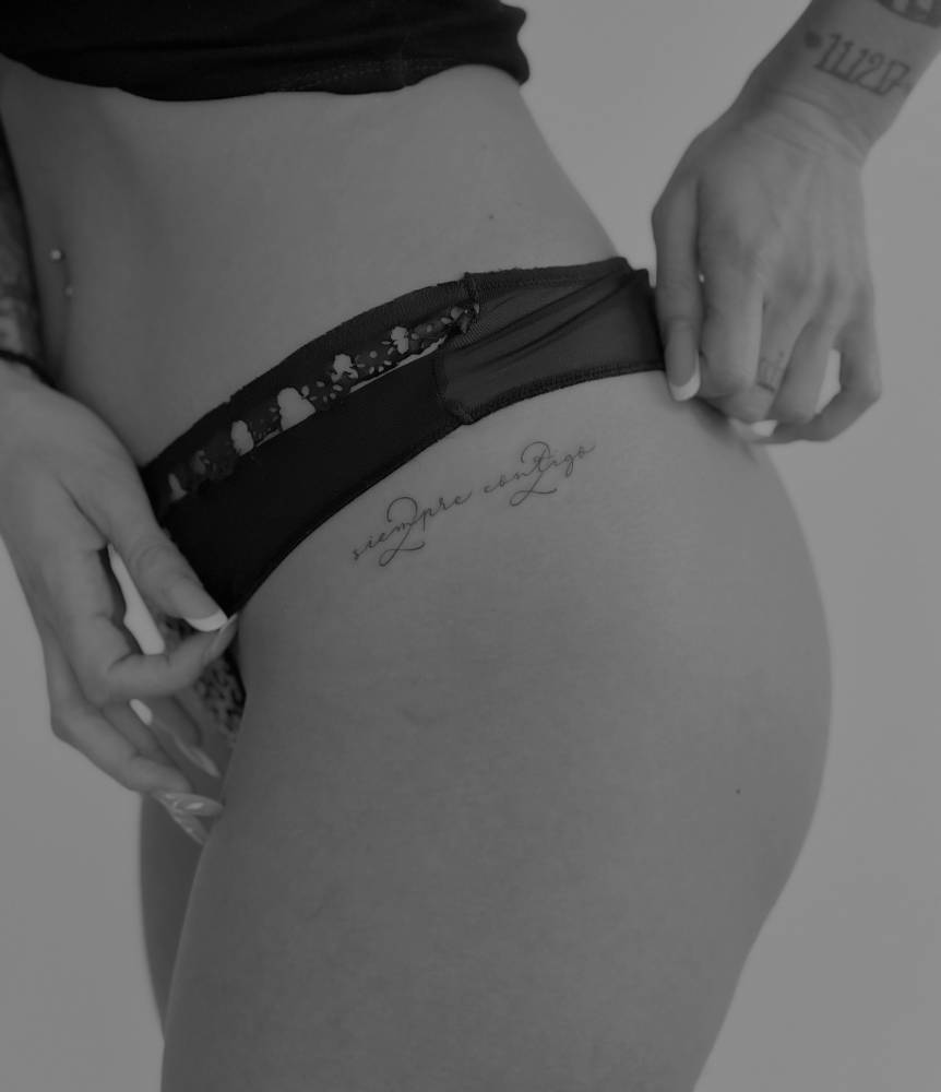 "Siempre contigo" handwritten lettering tattoo located on the hip.