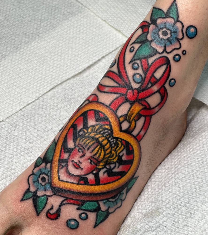 Traditional style heart pendant tattoo located on the foot.