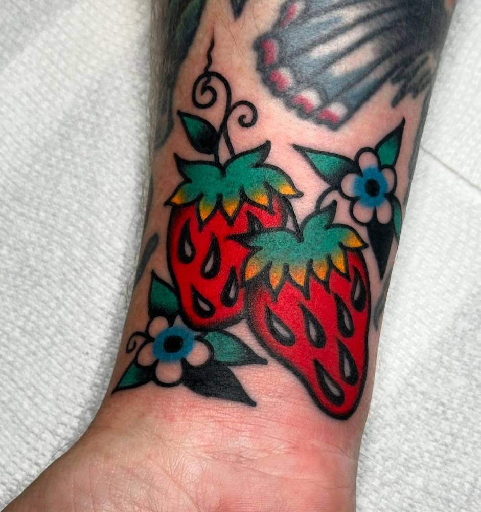 Strawberries tattoo in traditional style done on the wrist.