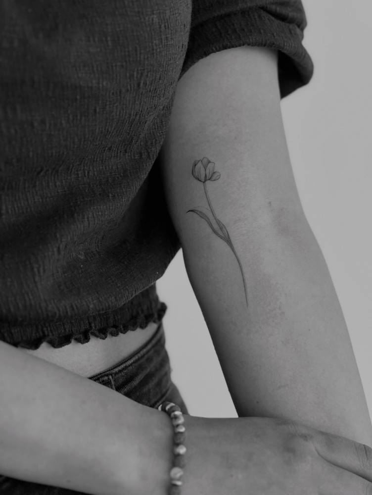Tulip flower tattoo in fine line style placed on the inner arm.