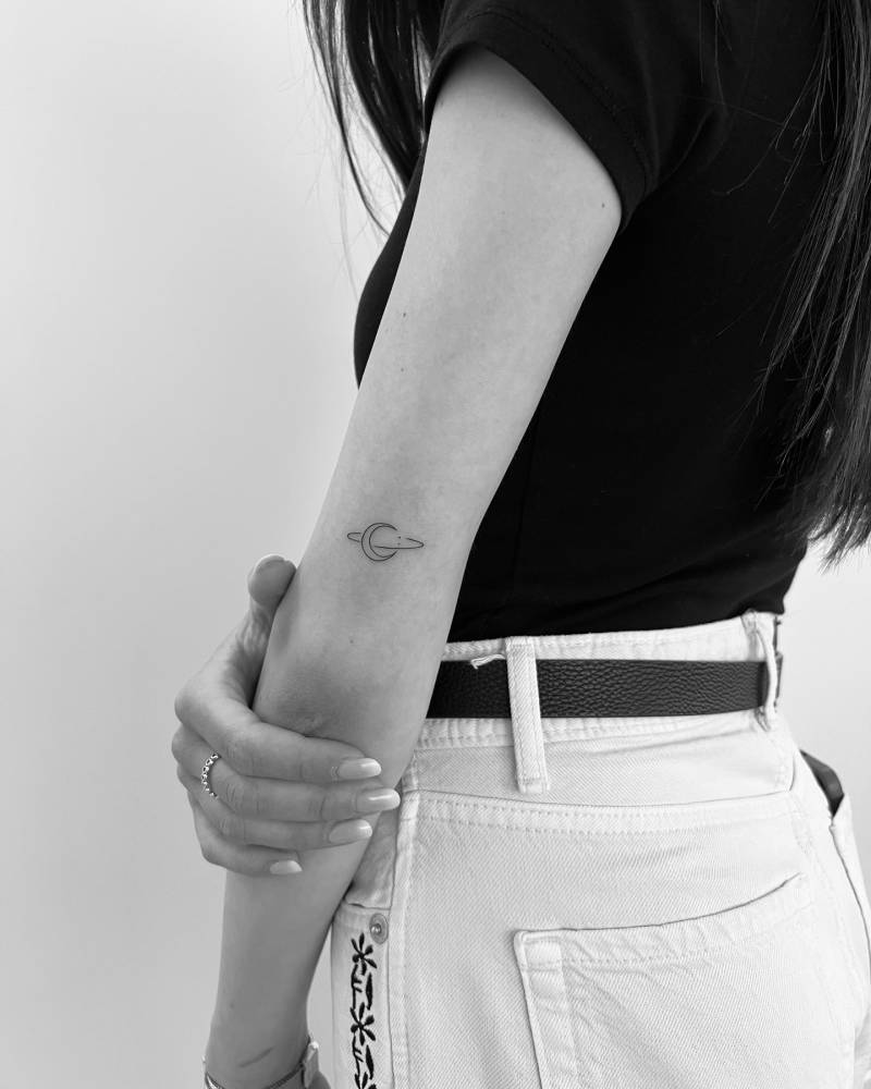 Minimalistic style Saturn moon tattoo located on the tricep.