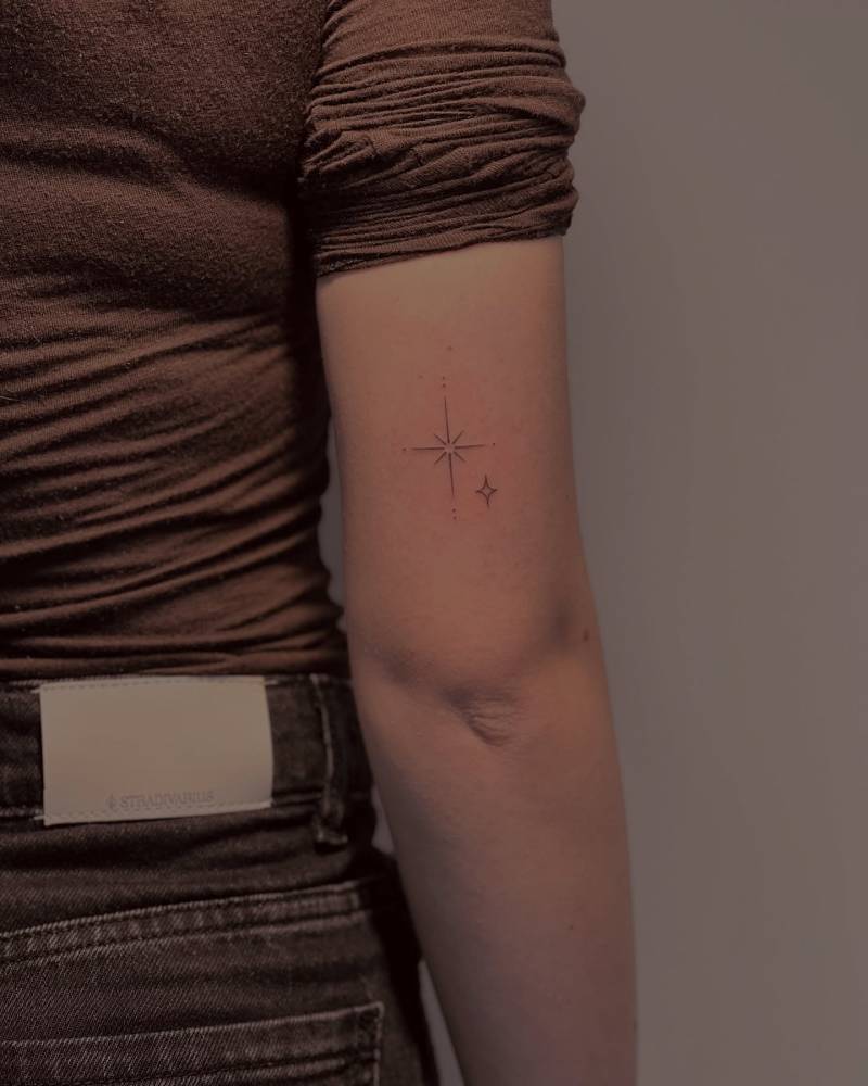 Sparkling stars tattoo in fine line style done on the tricep.
