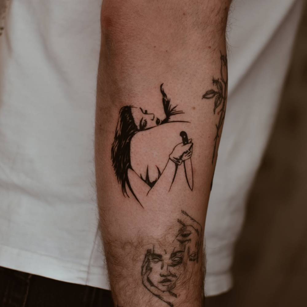 Backstabbing hug tattoo located on the forearm, blackwork style.