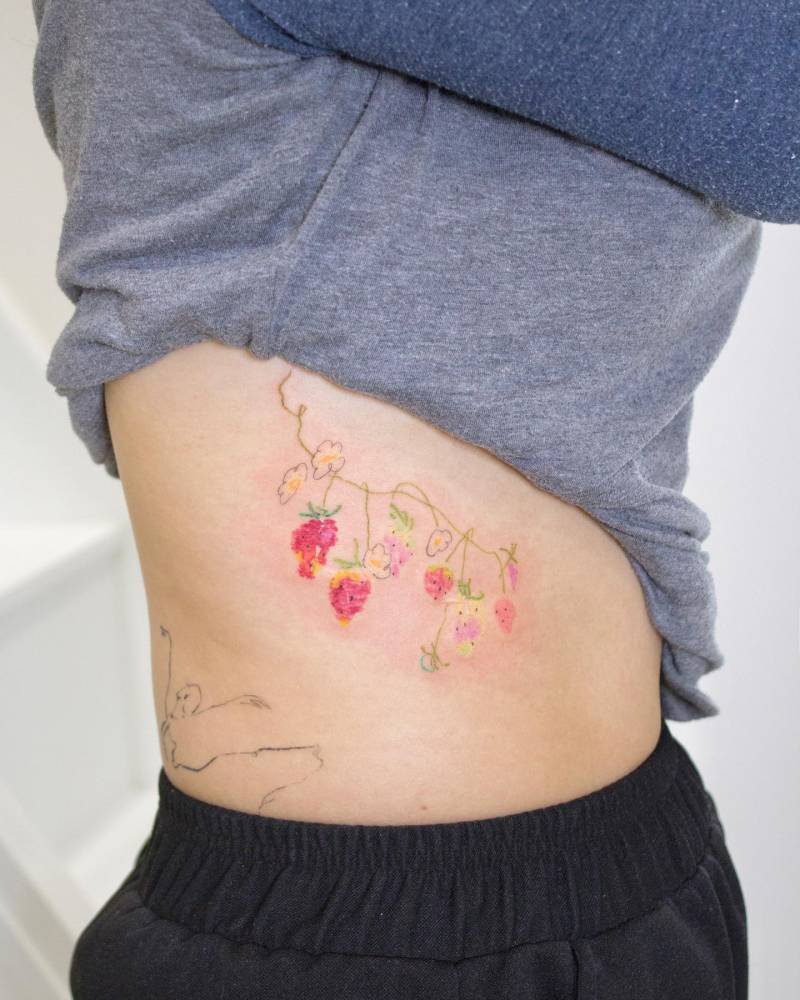 Watercolor style strawberries tattoo located on the rib.