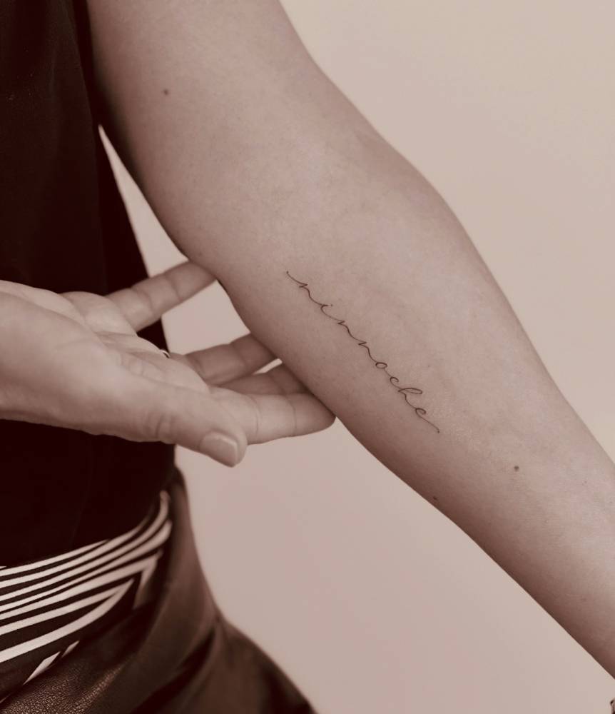 Lettering tattoo in script font located on the inner forearm.