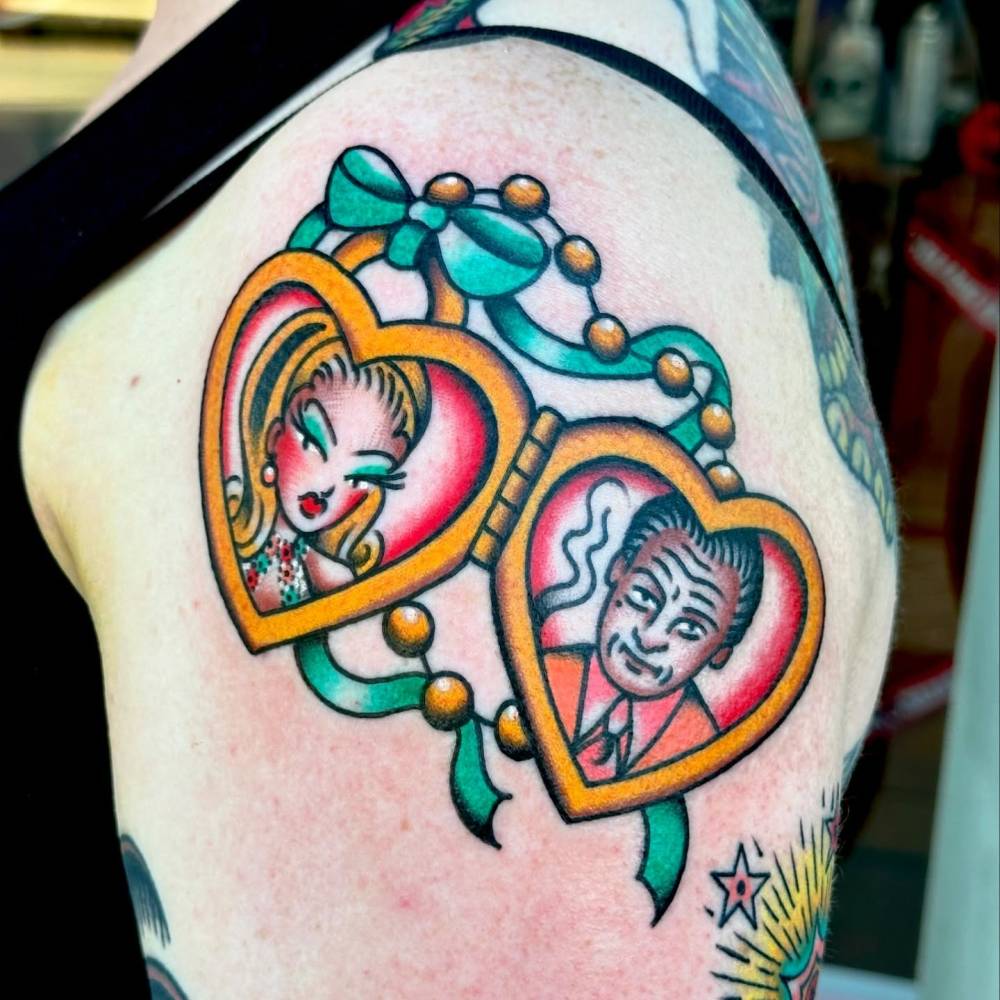 Heart pendant tattoo in traditional style located on the shoulder.