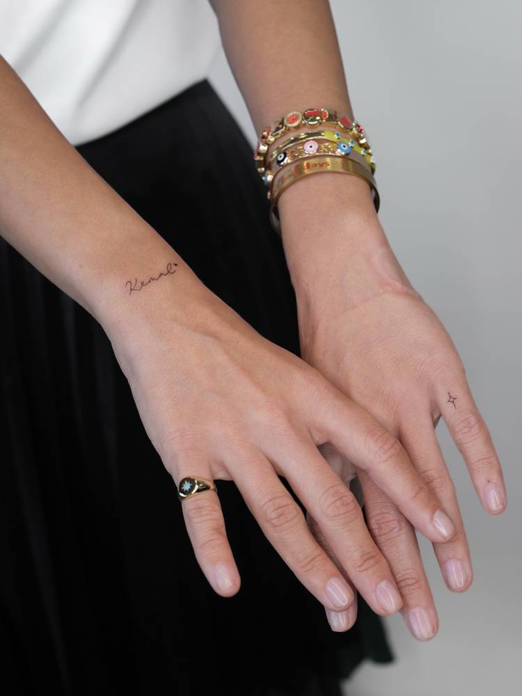 Word "kenal" and tiny star tattoos located on the wrist and finger.