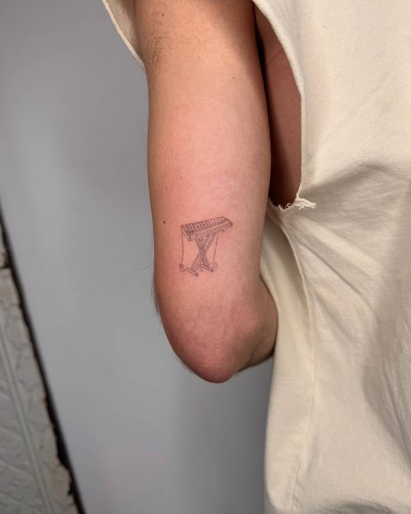 Synthesizer tattoo in fine line style placed on the tricep.