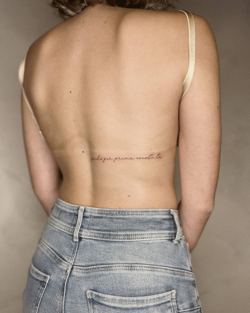 "Perché per prima esisti tu" lettering tattoo located on the back.
