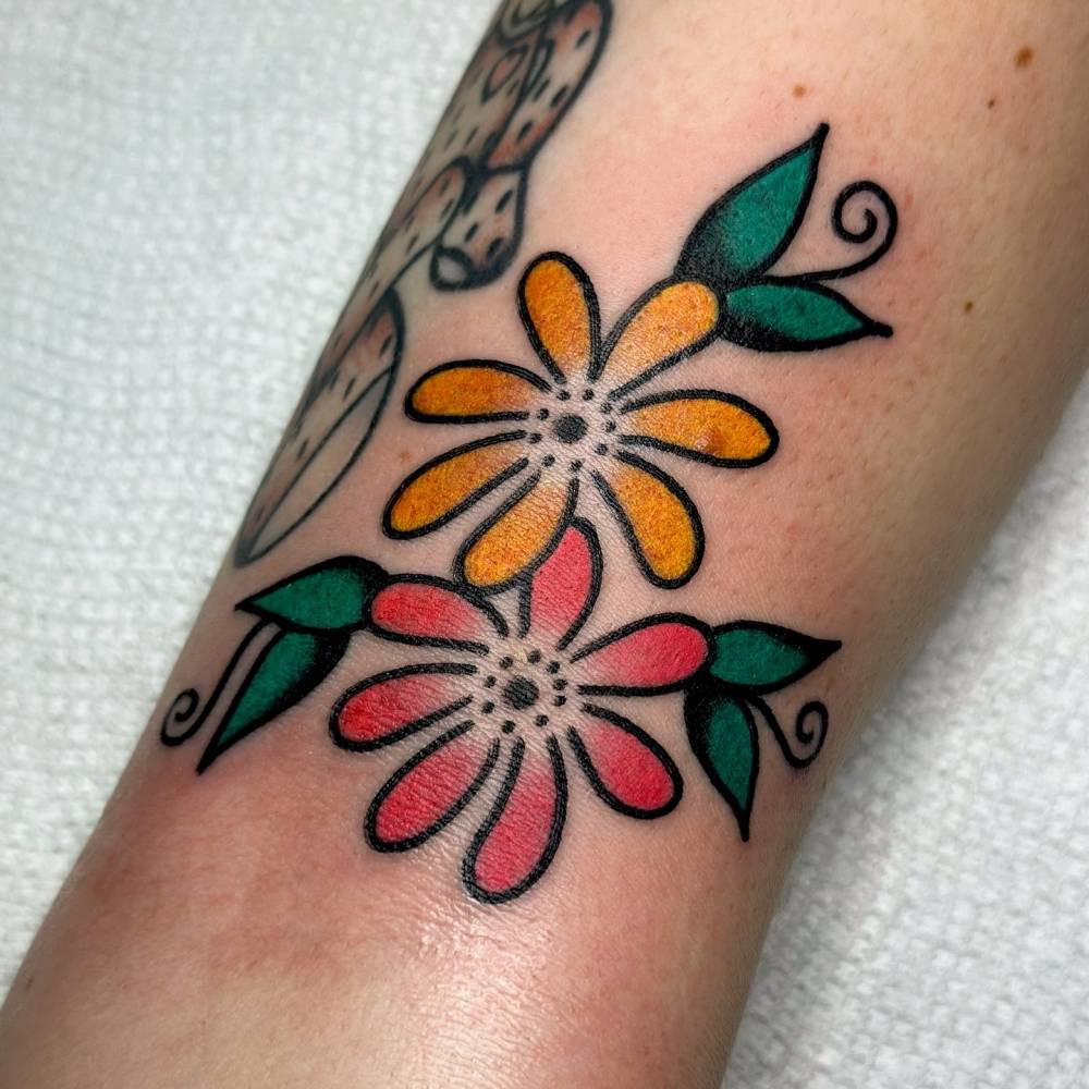 Flowers tattoo located on the bicep, done in traditional style.