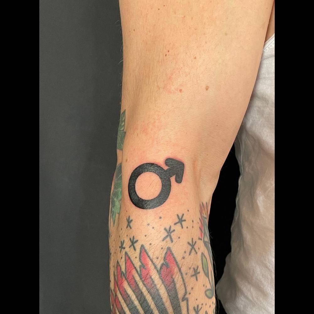 Blackwork style Mars planet symbol tattoo located on the forearm.