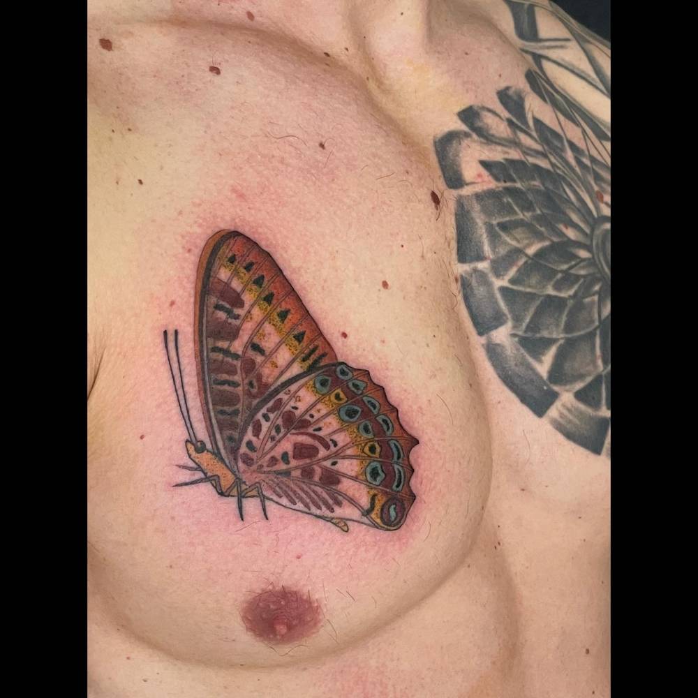 Illustrative style butterfly tattoo located on the chest.