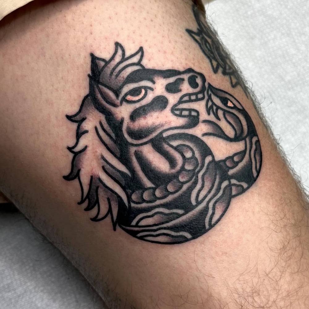 Horse and snake tattoo located on the thigh, done in traditional style.