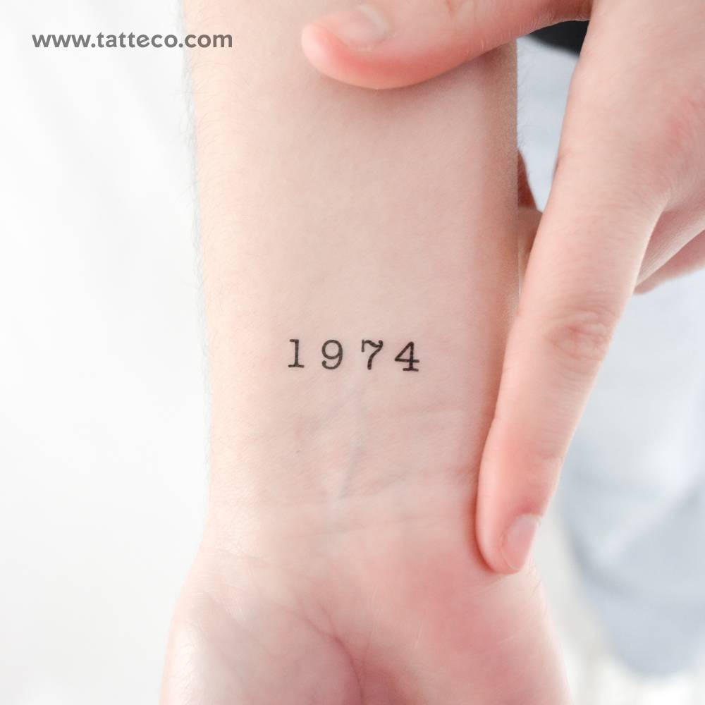 Typewriter font "1974" temporary tattoo located on the wrist.