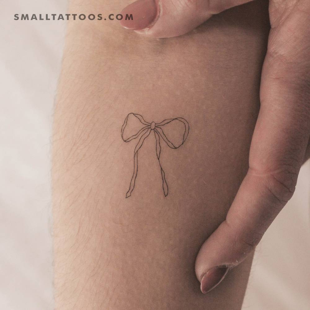 Fine line style ribbon bow temporary tattoo located on the inner forearm.