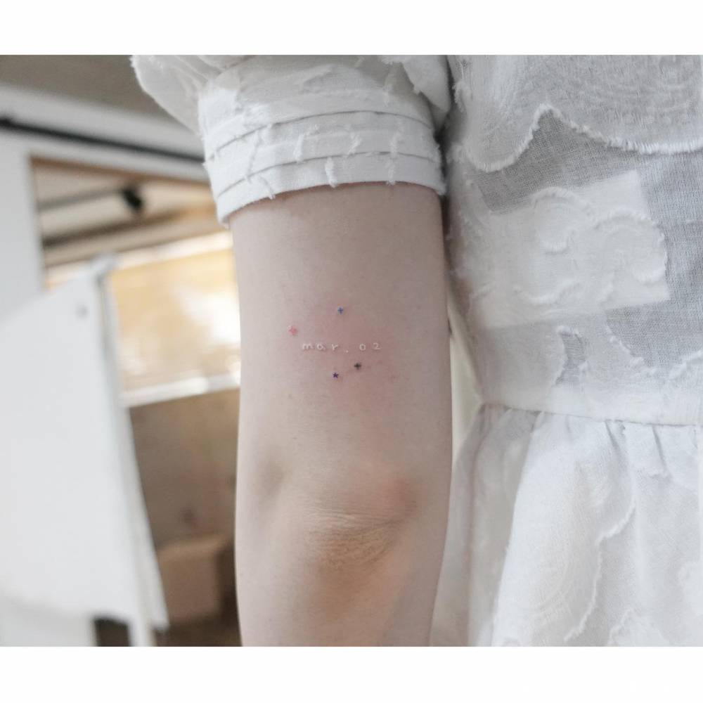 Stars and date tattoo located on the tricep, minimalistic style