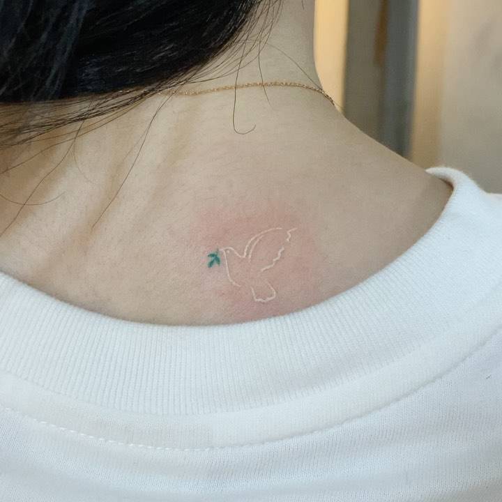 Little dove tattoo in minimalistic style placed on the upper back.