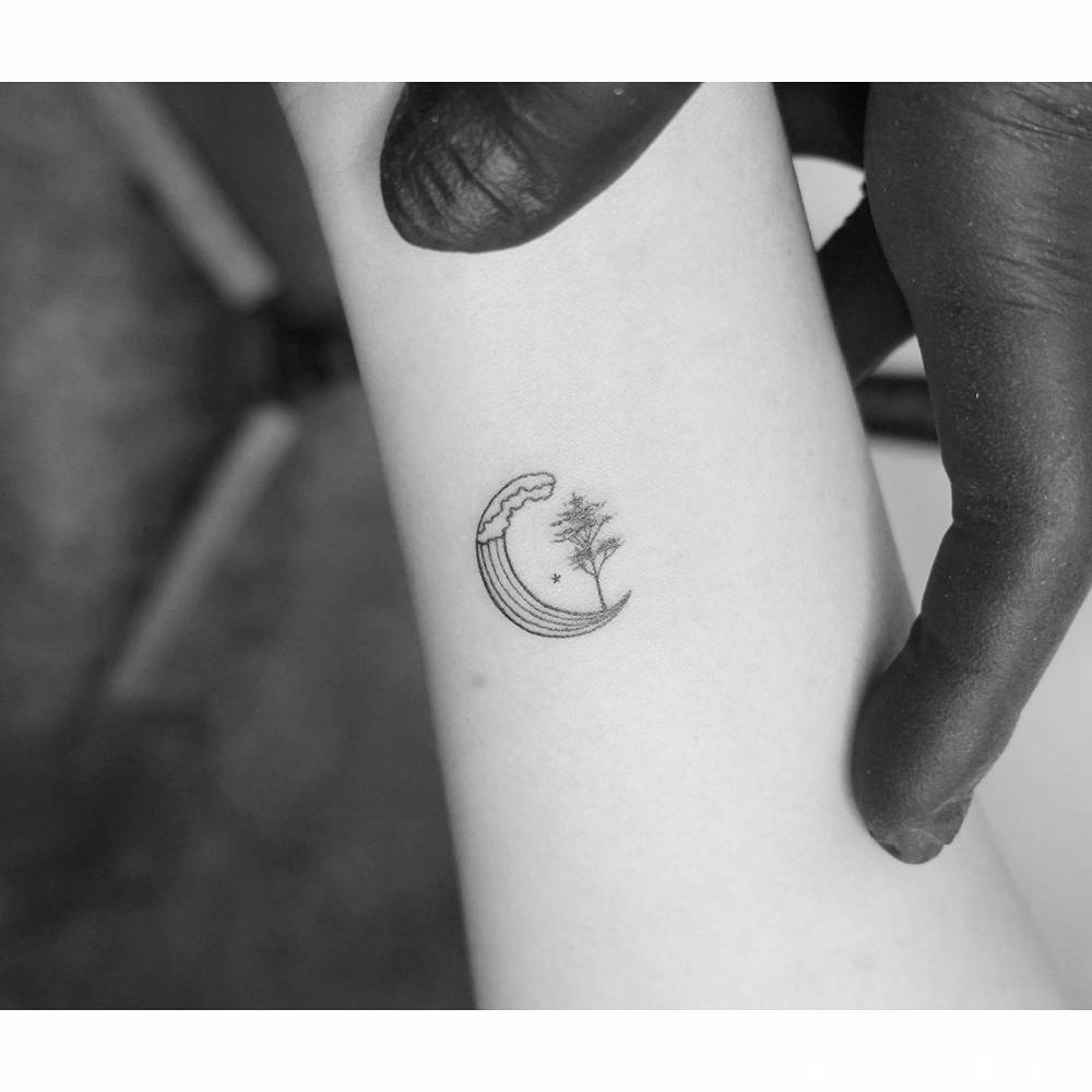 Tiny wave and tree tattoo in minimalistic style placed on the wrist.