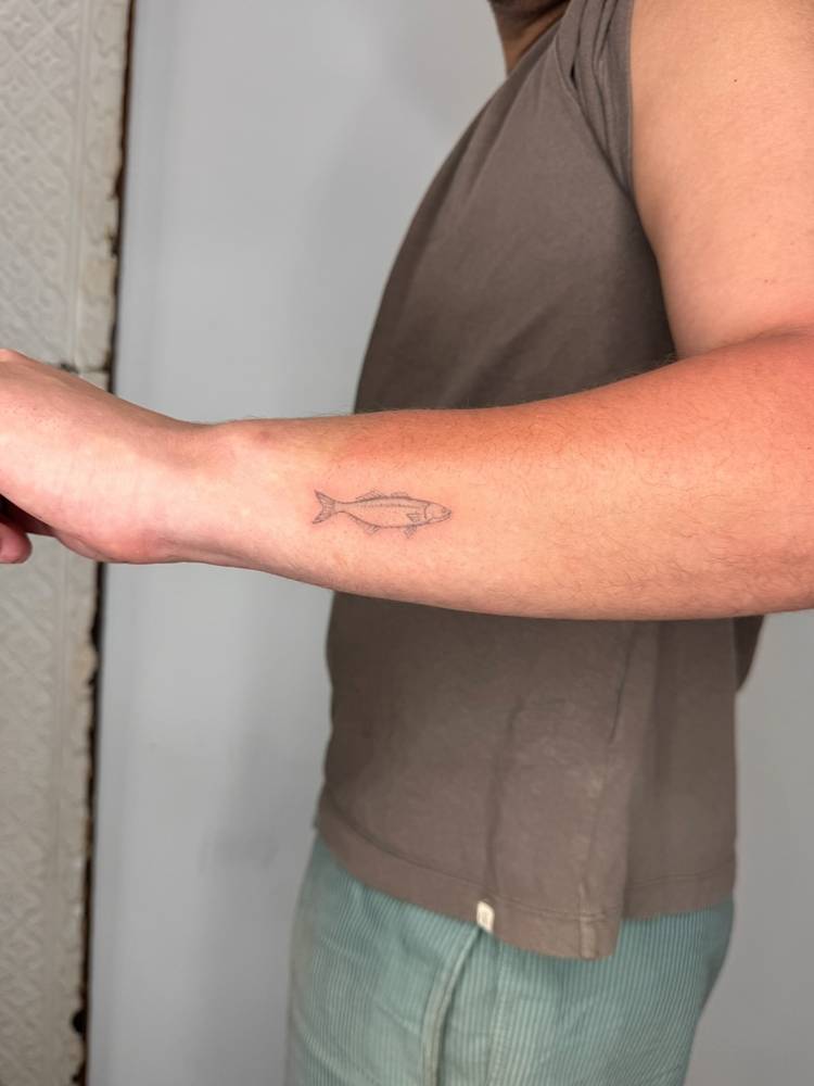 Single needle sardine tattoo located on the wrist.